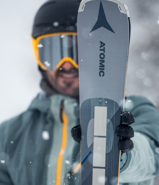 Skifahrer mit Brille hält einen Atomic-Ski vor sich im Schneetreiben