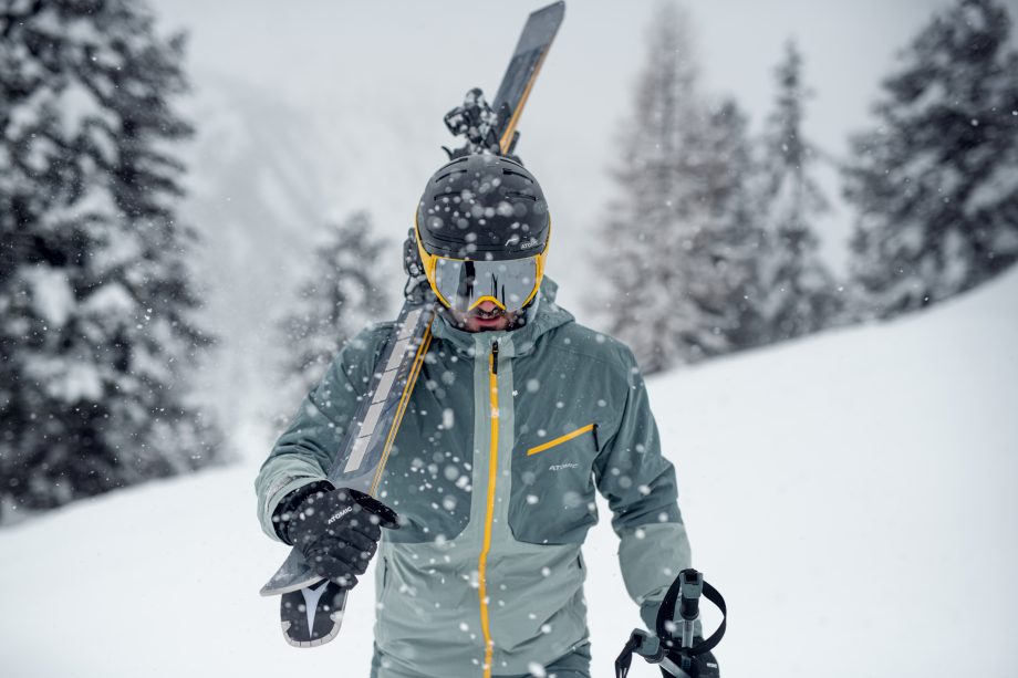 Skifahrer trägt seine Ski im verschneiten Winterwald