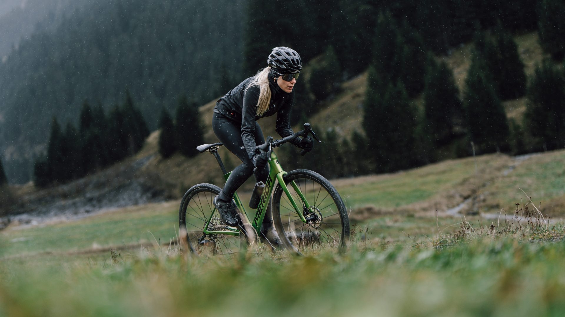 Radfahrerin auf einem Gravelbike auf einer Almwiese