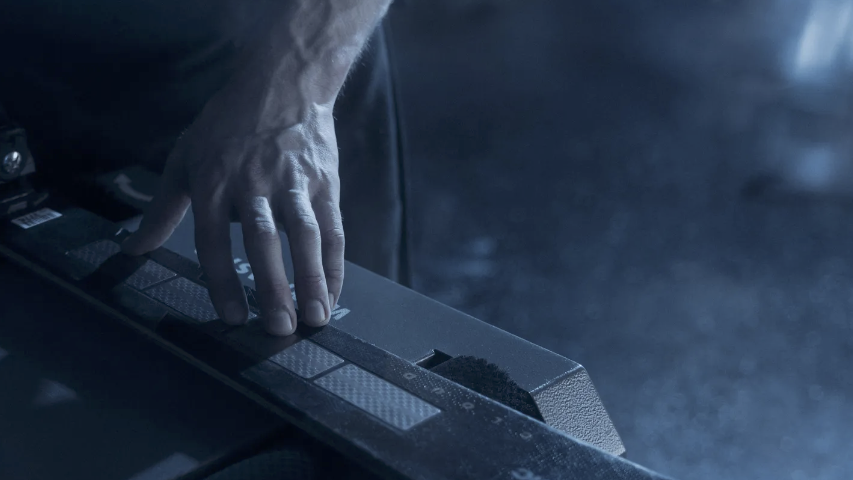 Hand bearbeitet einen Ski an der Servicemaschine in der Werkstatt